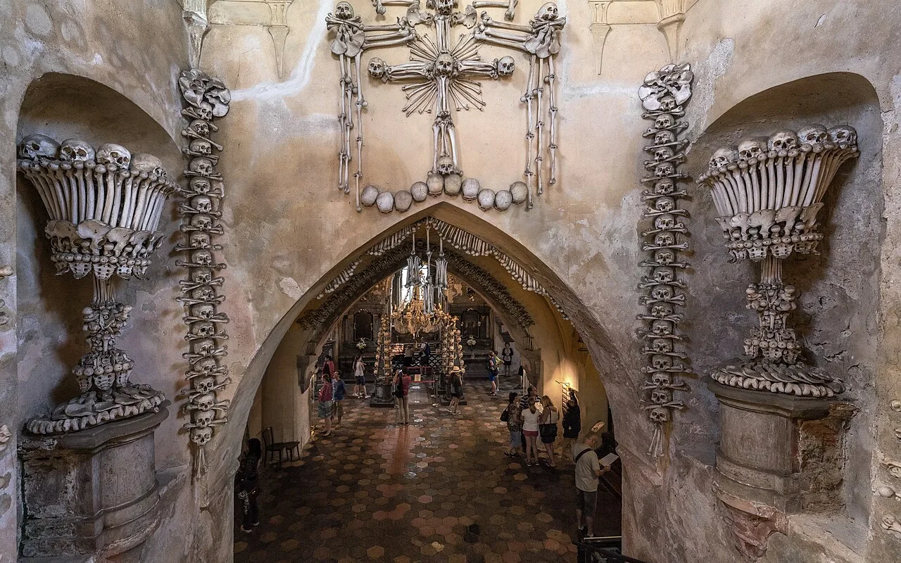 The vaulted interior of the Sedlec Ossuary, with bone pyramids beneath the arches and the chandelier at the centre