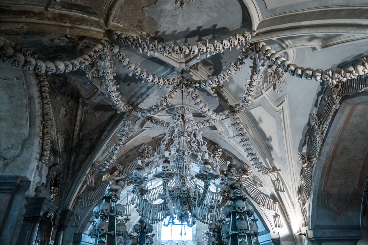 The interior of the Sedlec Ossuary near Kutná Hora — František Rint's great chandelier of human bones hanging beneath the vaulted, bone-garlanded ceiling of the chapel.